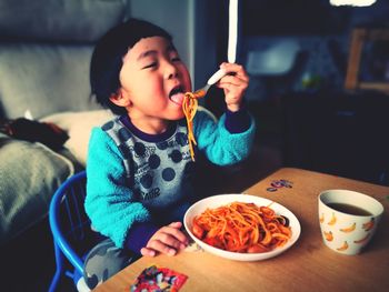 Close-up of cute baby boy eating food at home