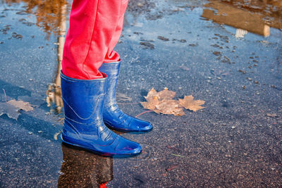 Low section of person wearing rubber boot while standing in puddle
