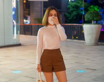 Young woman looking away while standing outdoors