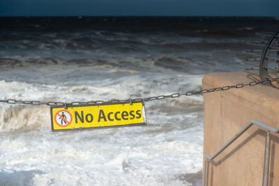 Information sign on beach against sky