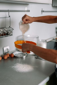 Midsection of person preparing food in kitchen at home