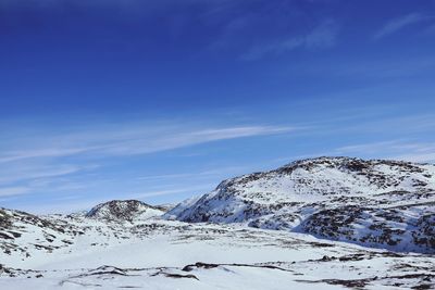 Scenic view of snow covered mountains against blue sky