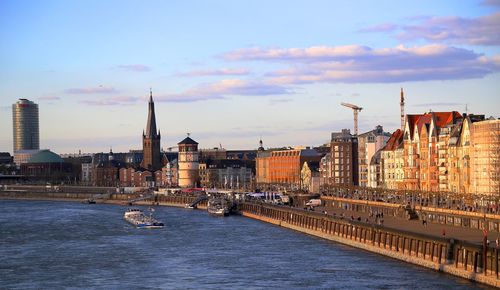 View of buildings at waterfront against cloudy sky