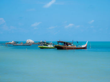 Boats moored in sea against blue sky