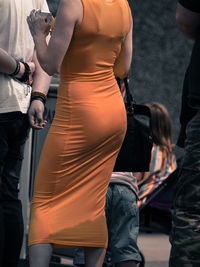Midsection of woman in orange dress standing outdoors