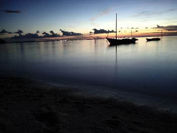 Boats moored in sea at sunset