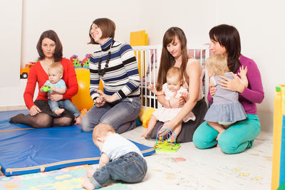 Full length of friends sitting on floor