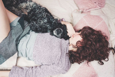 Woman with dog lying on bed at home