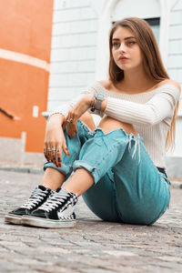 Full length of young woman sitting in city