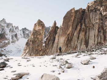 Rear view of man standing against rock formations during winter