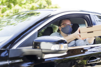 Woman picks up pizza while wearing mask