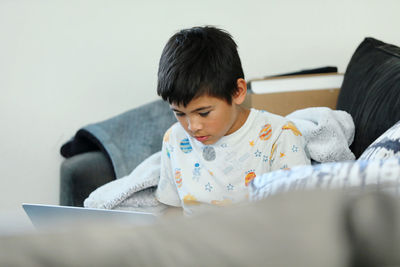 Portrait of cute girl sitting on sofa at home