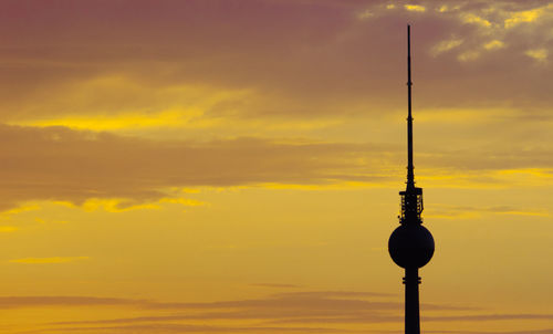 Low angle view of silhouette tower against orange sky