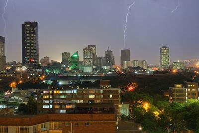 Illuminated buildings in city against sky at night