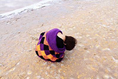 High angle view of woman sitting at sandy beach