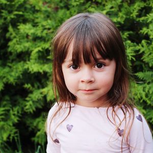 Close-up portrait of cute girl against plants