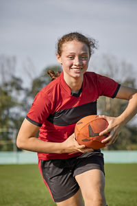 Happy girl with rugby ball practicing on sunny day