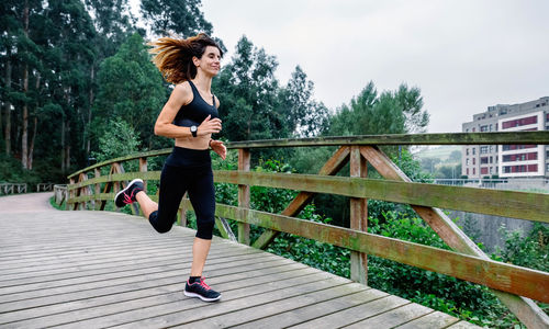 Full length of woman running on footbridge