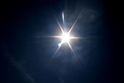 Low angle view of sun shining in blue sky