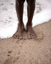 Low section of man standing on wet sand