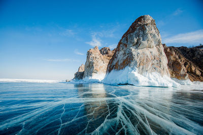 Scenic view of rock formation in sea against blue sky