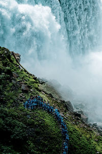 Group of people on mountain against cloudy sky