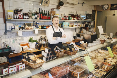 Portrait of confident male owner standing at display cabinet in store