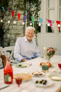 Portrait of smiling senior man sitting at dining table in back yard