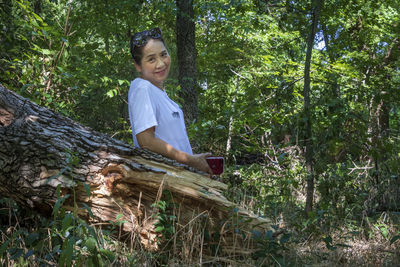 Portrait of senior woman standing against trees in forest