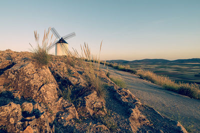 Traditional windmill on landscape against sky during sunset