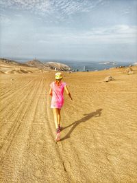 Rear view of woman standing on field against sky