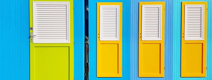 Closed yellow doors of blue beach huts