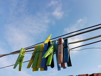 Low angle view of clothespins on clothesline against sky