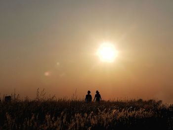 Men on field against sky during sunset