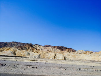 Scenic view of arid landscape against clear blue sky