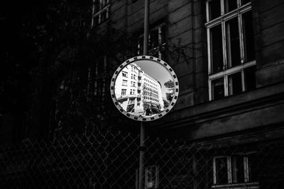 Low angle view of road mirror with reflection against building