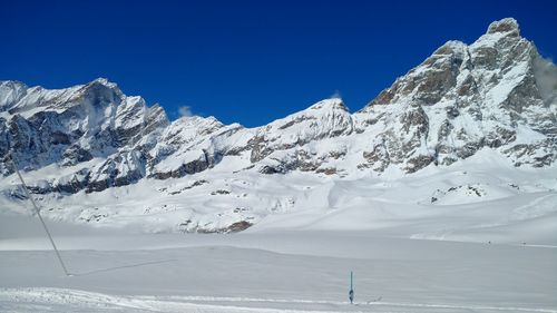 Scenic view of snowcapped mountains against clear blue sky