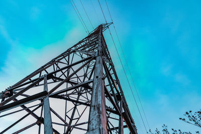 Low angle view of electricity pylon against blue sky