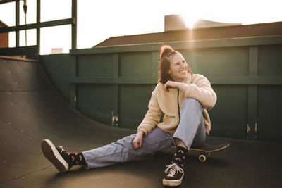 Smiling teenage girl sitting on skateboard