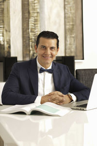 Portrait of businessman with book on table