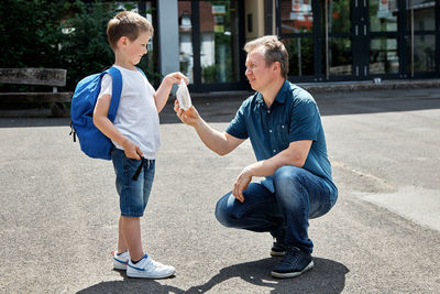 Dad gives his son, boy a lunch bag, breakfast with him to school. care of parents 