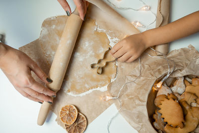 The hands of the child and the mother prepare cookies from the dough, roll out the dough on paper