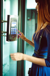 Side view of young woman using elevator buttons