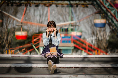 Full length of girl in school uniform sitting on stairs 