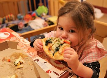 Cute girl eating pizza at home