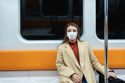 Portrait of woman wearing mask sitting in train