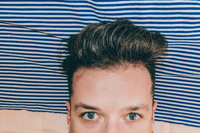 Close-up portrait of man against striped curtain
