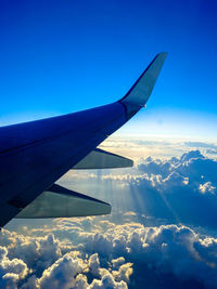 Airplane wing over clouds against blue sky