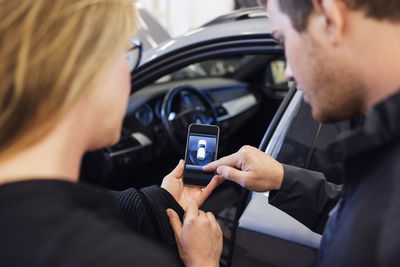 High angle view of mechanic explaining mobile app to customer