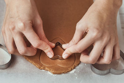 Making gingerbread cookies in shape of a heart for valentines day. woman hand use cookie cutter
